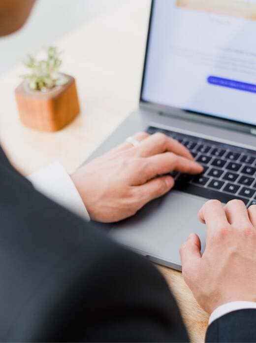 Manager sitzt vor Laptop und möchte Kontakt zum Texter für Deutschland, Österreich und die Schweiz aufnehmen über Kontaktformular.