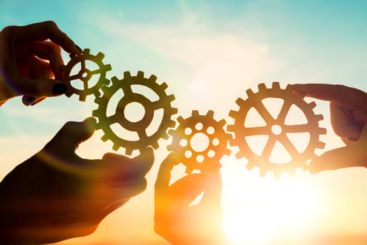 Werbetexte schreiben lassen vom Werbetexter für Werbekampagnen und Werbeaktionen – Erfolgs-Symbol: Hände halten Zahnräder.